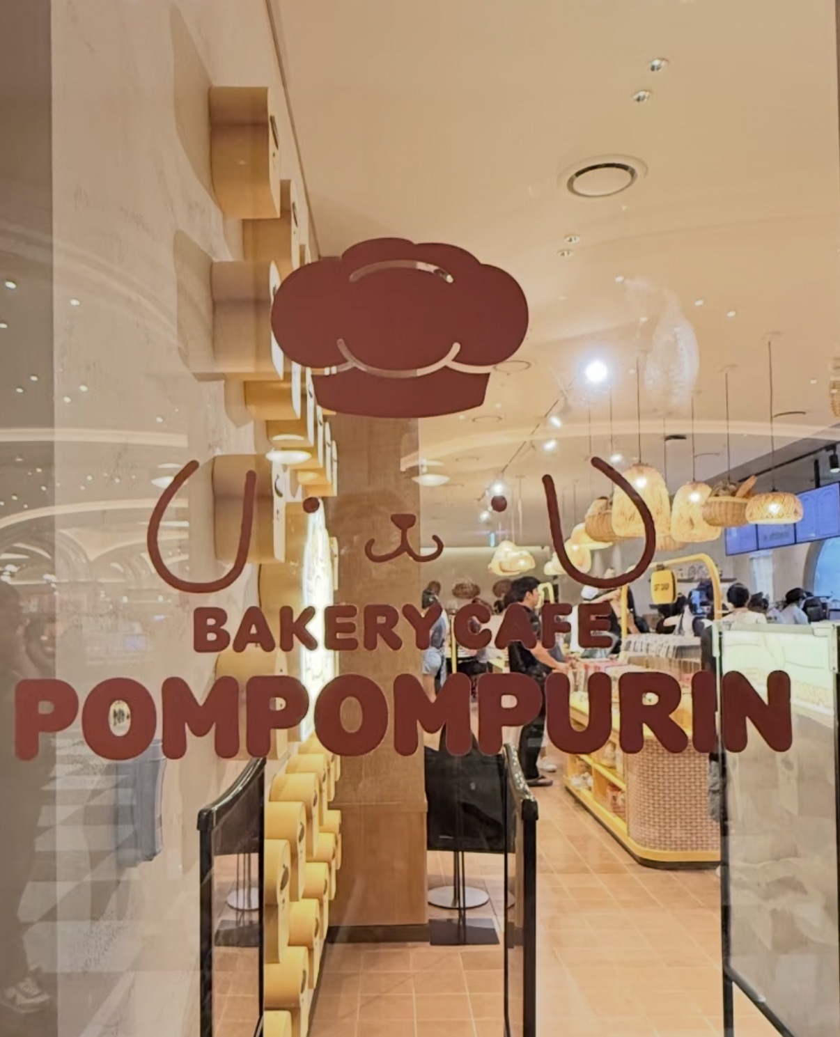 ガラスに描かれた「BAKERY CAFE POMPOMPURIN」のロゴ。